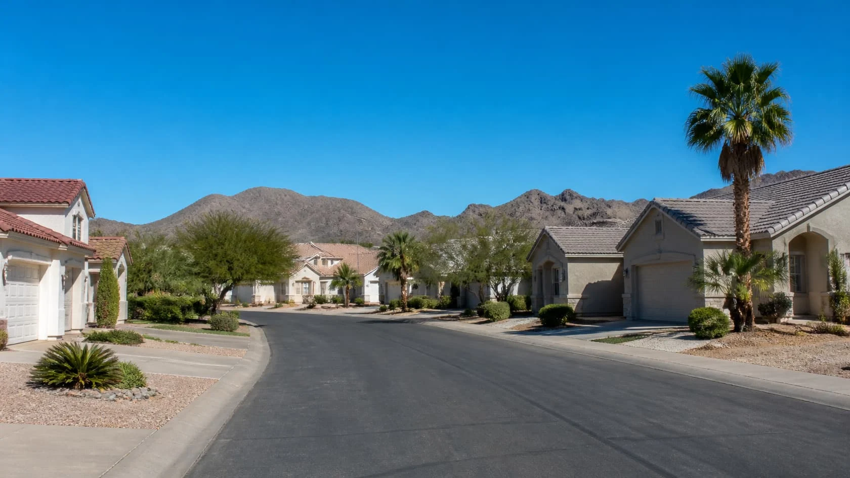 Quiet street with shingle and tile homes, palms and mountains