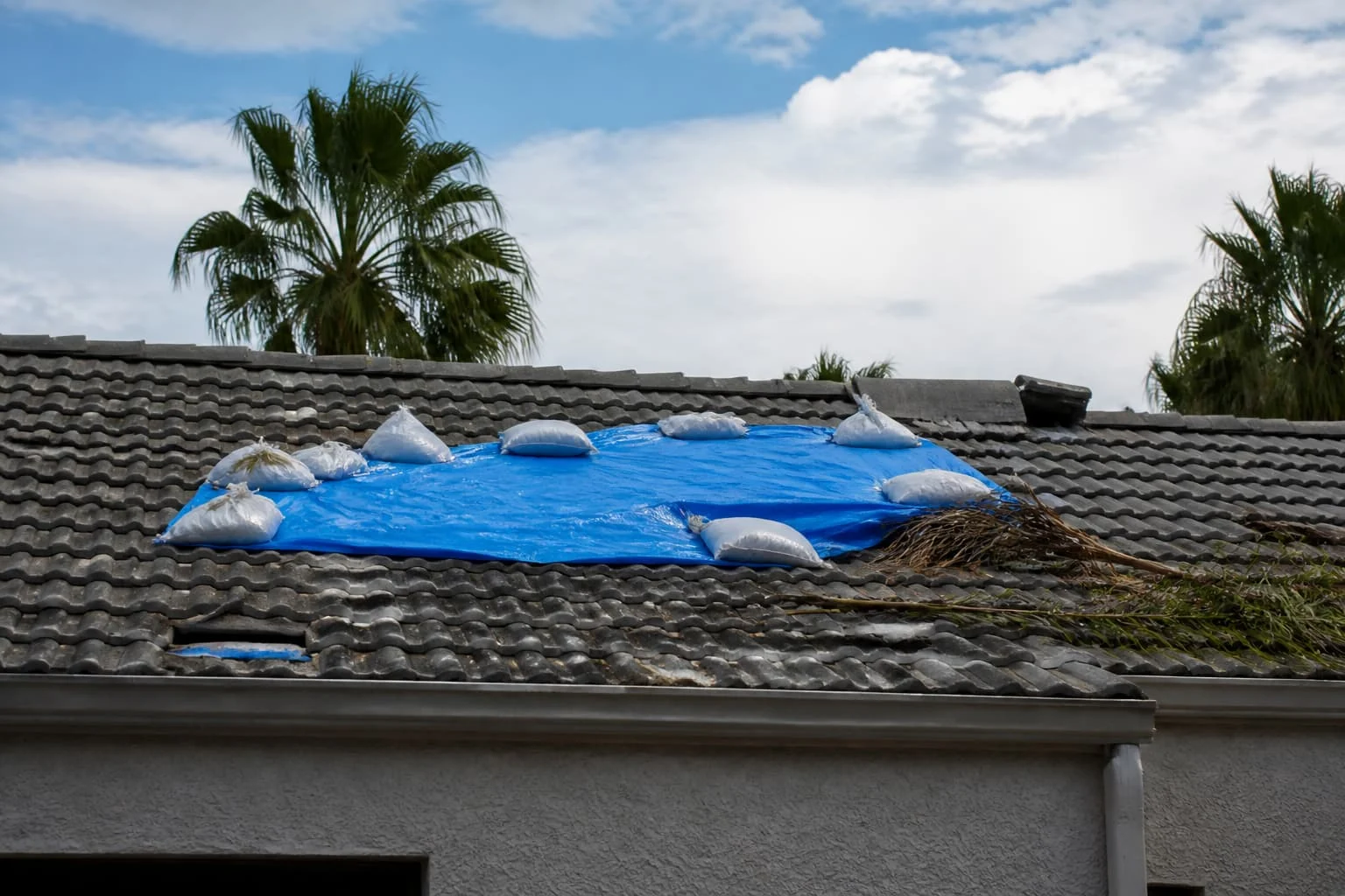 Blue tarp secured with sandbags on a tile roof