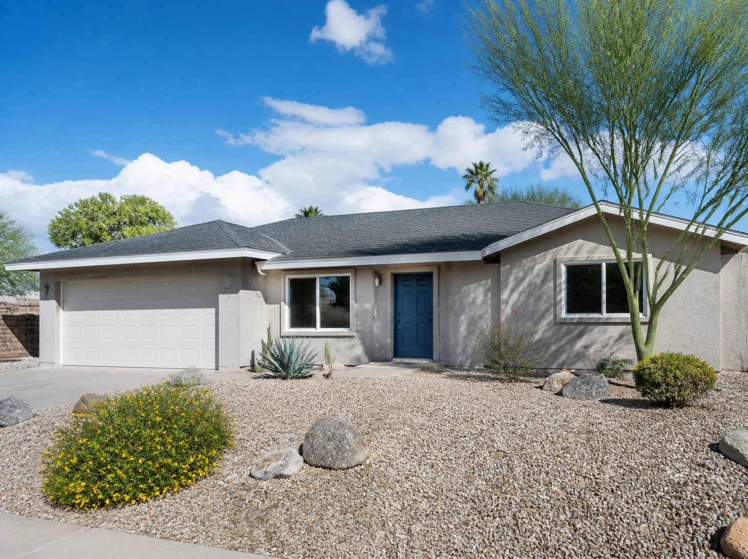 Gray stucco home with a charcoal shingle roof and blue door